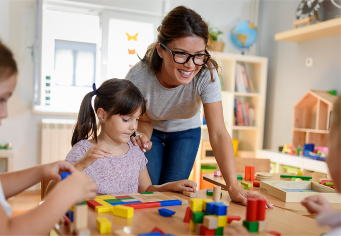 Teacher looking over students at the building blocks table.
